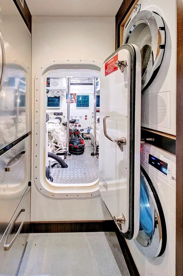 The yacht features a well-equipped laundry room with modern appliances and a view into the engine room. aboard MISTY K Yacht for Sale