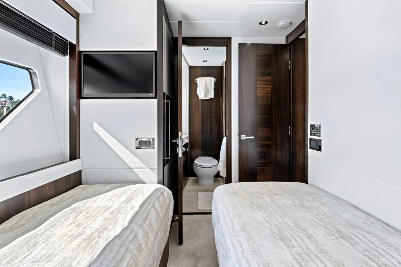 The guest stateroom features twin beds, a wall-mounted TV, and an en-suite bathroom with modern finishes. aboard MISTY K Yacht for Sale