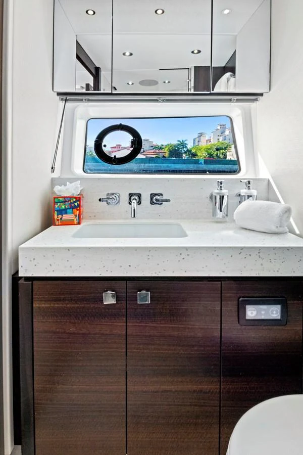 A modern yacht bathroom with a sleek vanity and a scenic view through the porthole. aboard MISTY K Yacht for Sale
