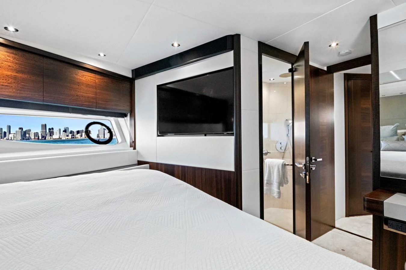 A luxurious stateroom featuring a large bed, a flat-screen TV, and a view of the city skyline through the window. aboard MISTY K Yacht for Sale