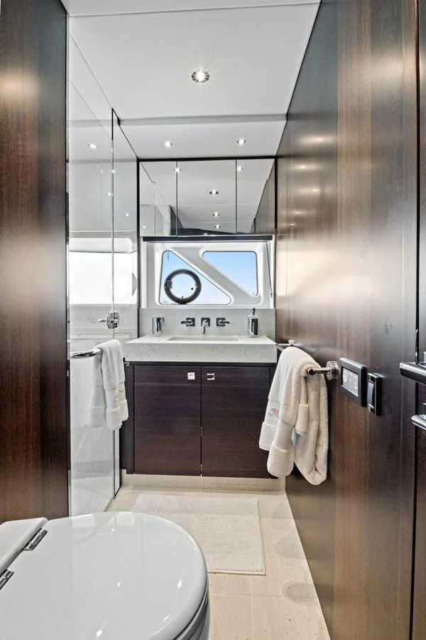 The yacht's bathroom features sleek wood paneling, a modern sink, and a porthole window for natural light. aboard MISTY K Yacht for Sale