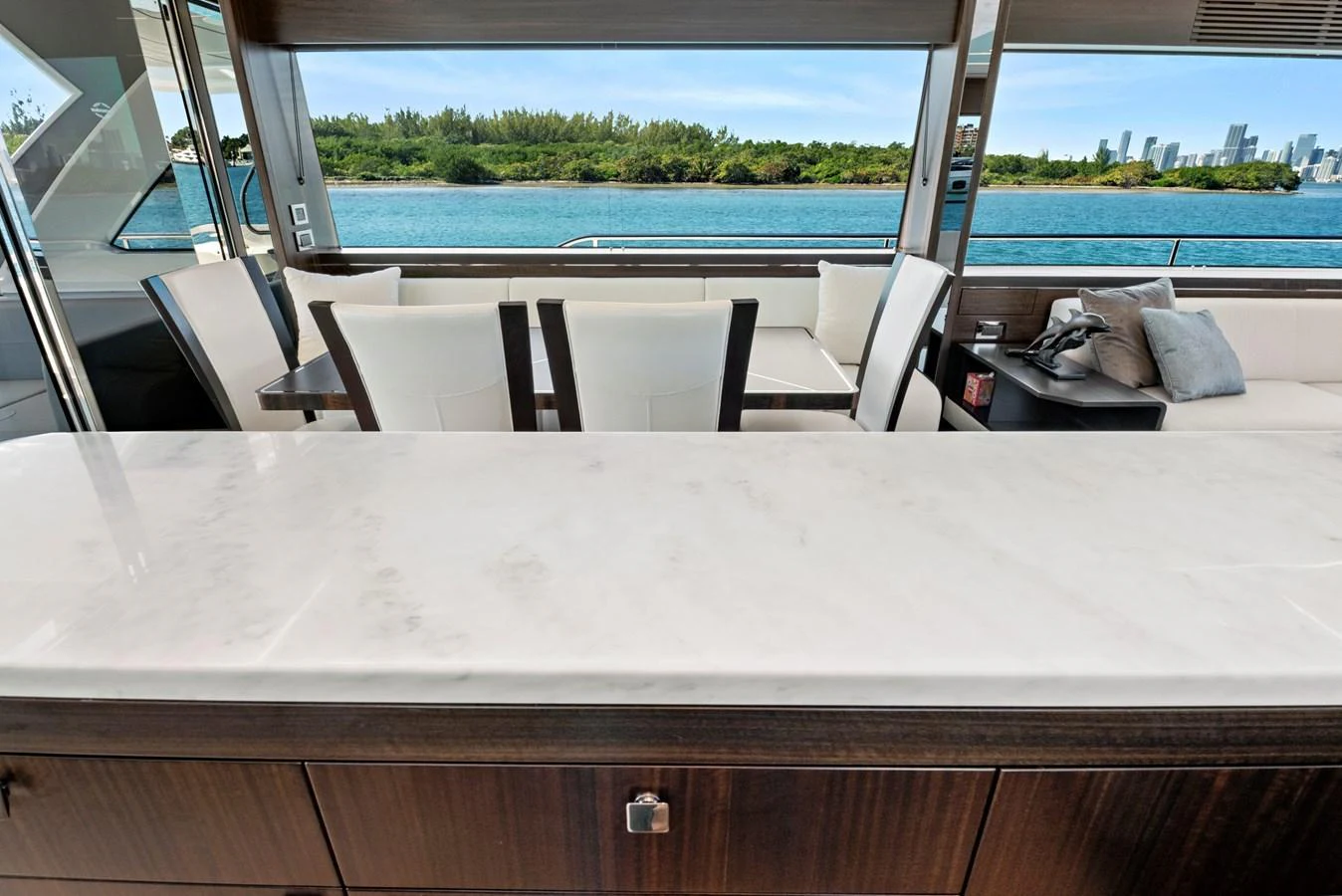 A luxurious interior space with a view of the water and city skyline through large windows. aboard MISTY K Yacht for Sale