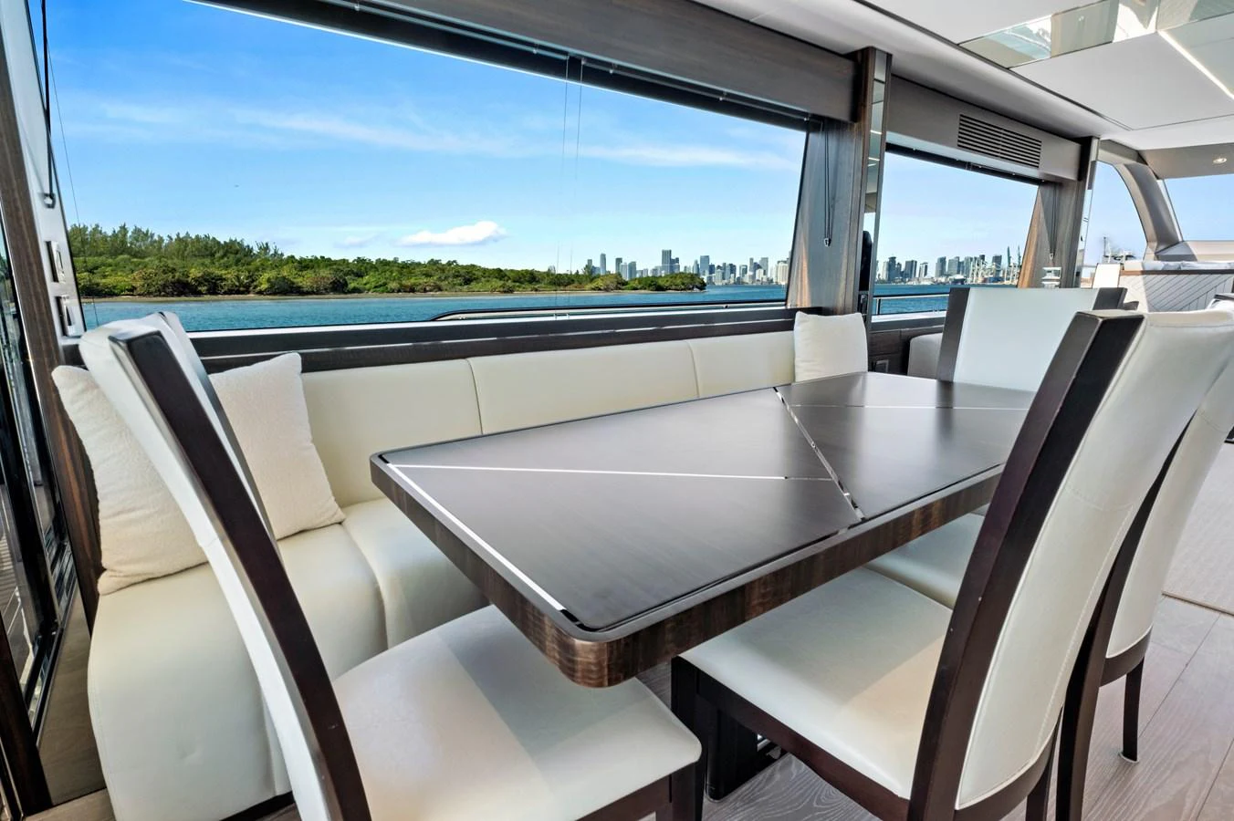 The yacht's dining area offers a luxurious setting with a stunning view of the water and skyline. aboard MISTY K Yacht for Sale