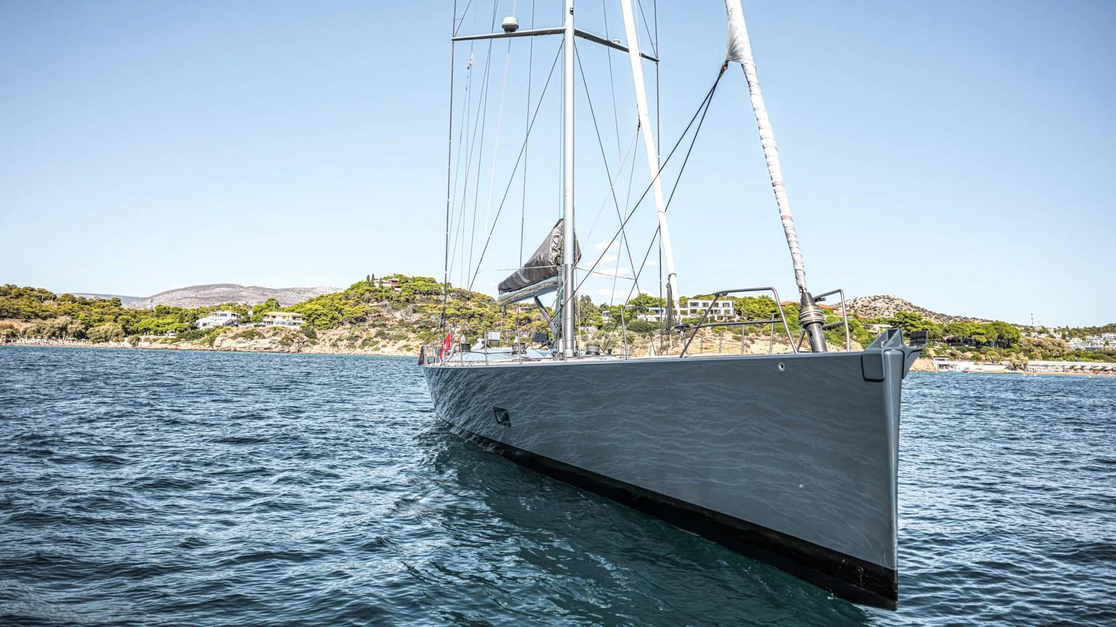 A sleek, modern yacht glides gracefully on calm waters with a scenic coastal backdrop. aboard AUGUSTA WALLY Yacht for Sale