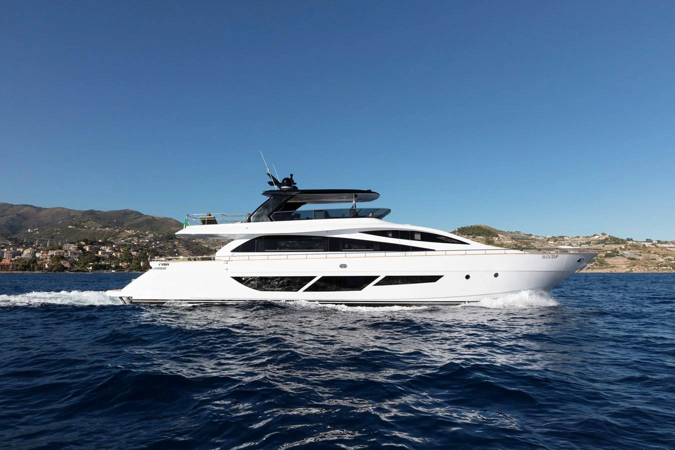 A sleek and modern yacht cruising on the open water with a scenic coastline in the background. aboard MARIPOSA Yacht for Sale