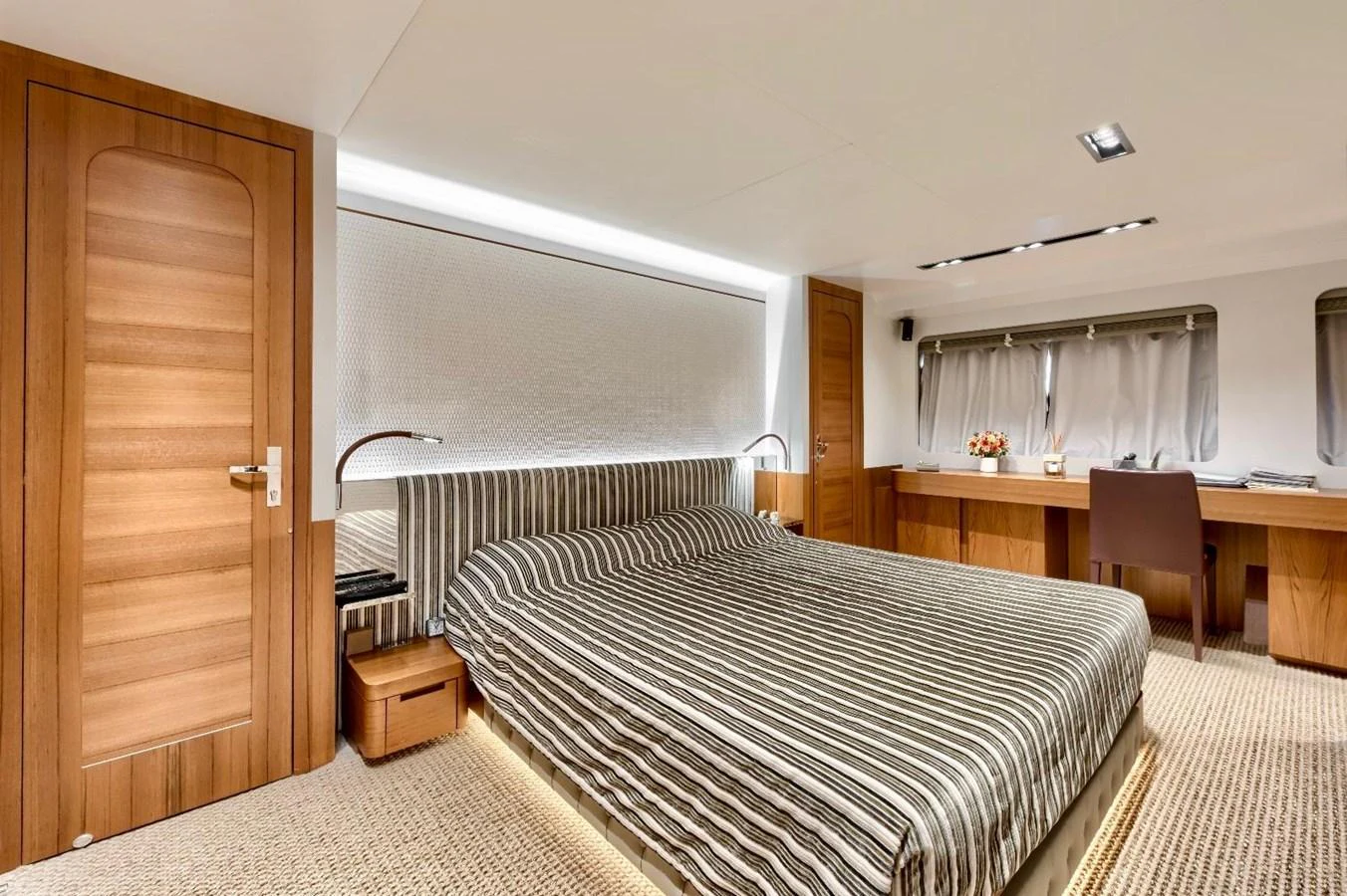 The master stateroom features a spacious bed with elegant striped bedding and ample natural light. aboard MARIPOSA Yacht for Sale