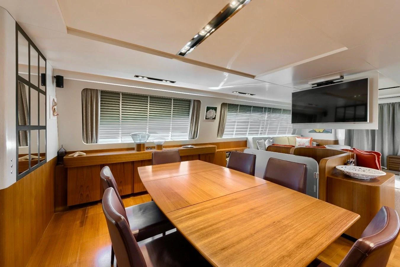 The yacht's dining area features a sleek wooden table and comfortable seating, perfect for enjoying meals with a view. aboard MARIPOSA Yacht for Sale