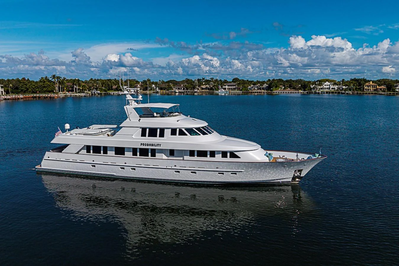 A sleek and elegant yacht cruises on calm waters under a clear blue sky. aboard PROBABILITY Yacht for Sale