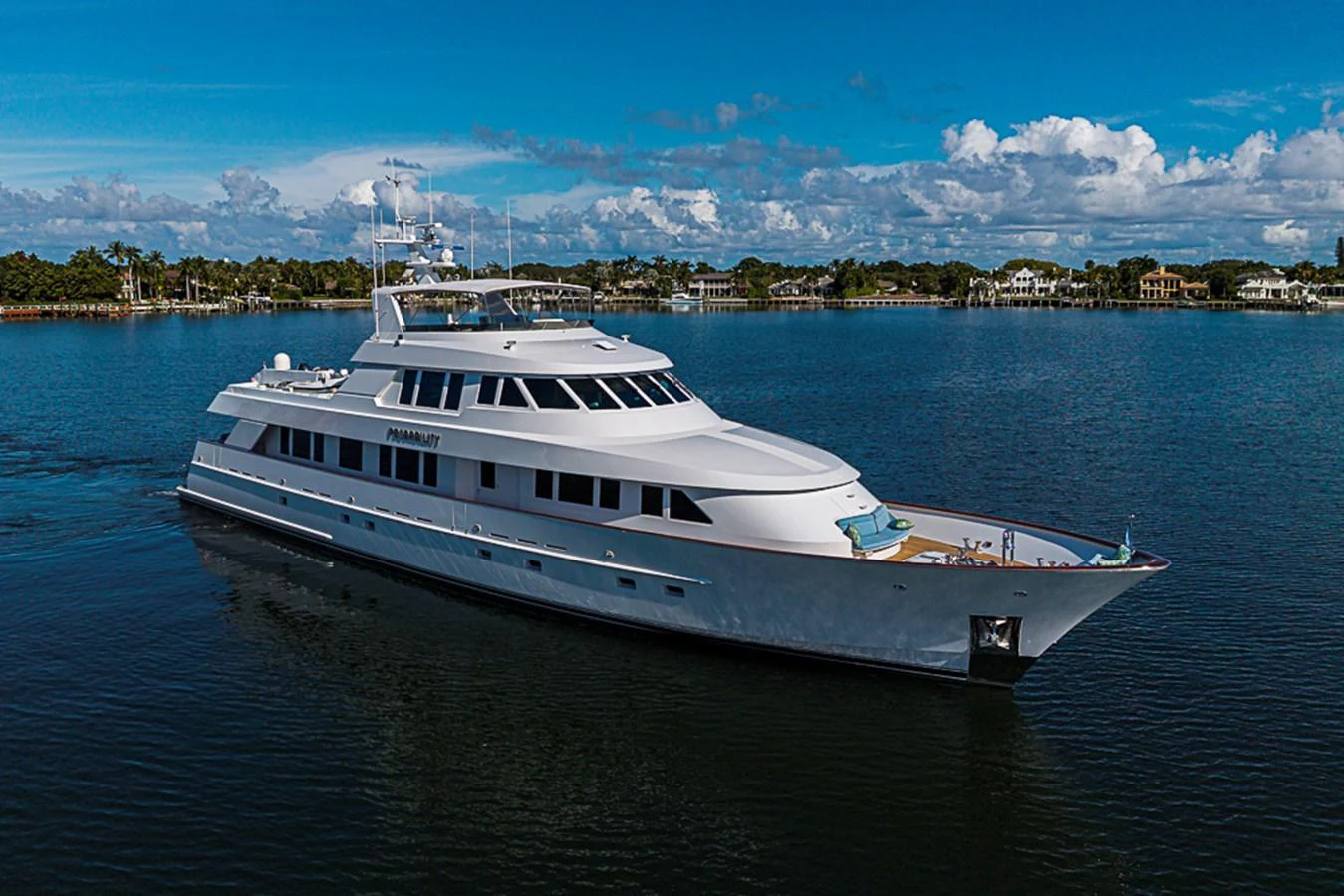 A sleek and elegant yacht glides gracefully on calm waters under a clear blue sky. aboard PROBABILITY Yacht for Sale