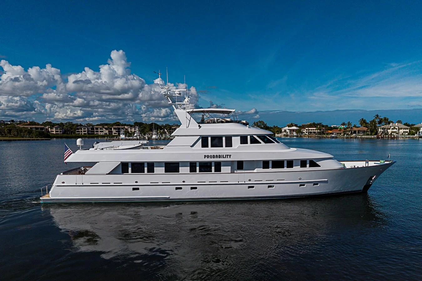 A sleek and elegant yacht cruising on calm waters under a clear blue sky. aboard PROBABILITY Yacht for Sale