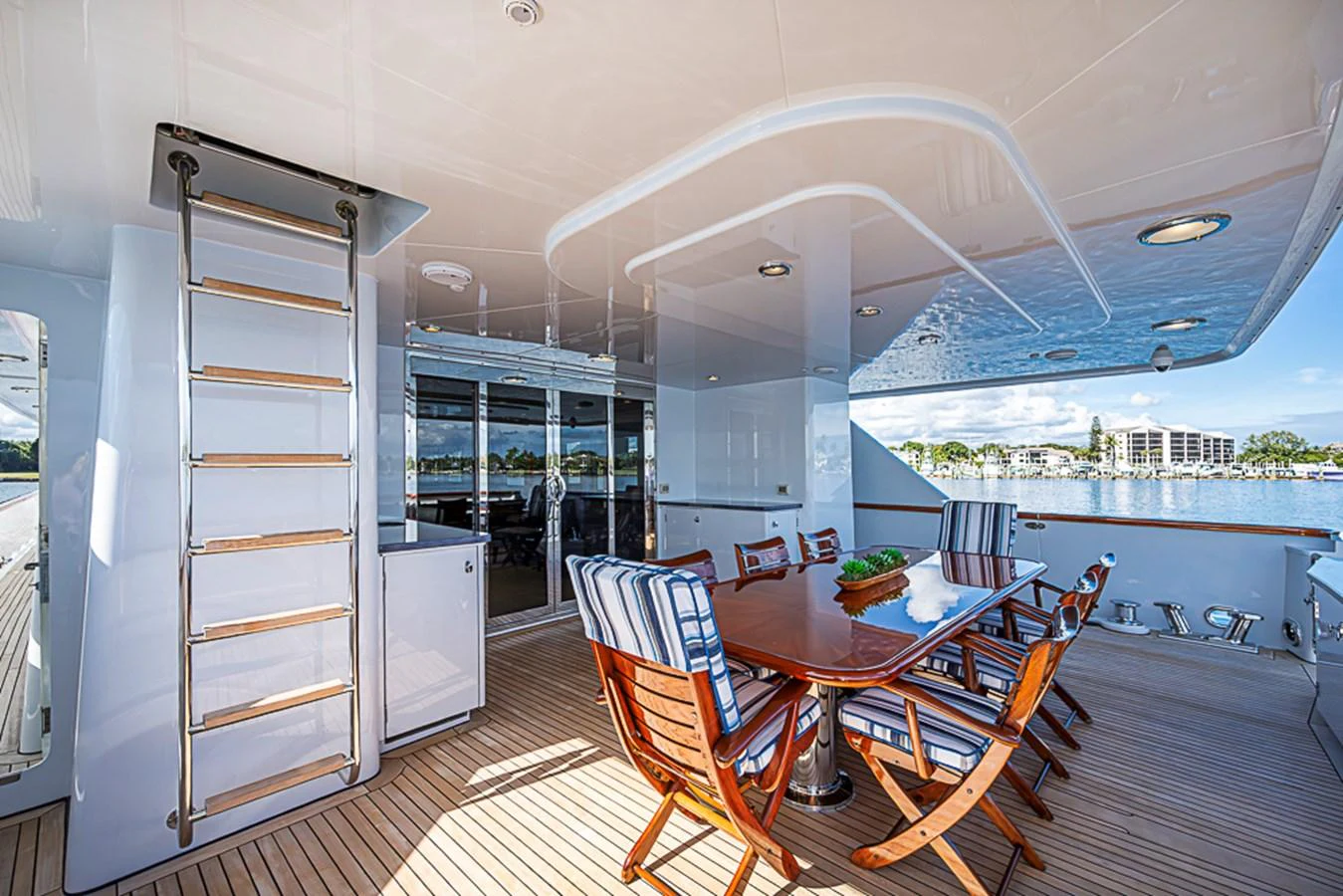The aft deck features a stylish dining area with a polished wooden table and cushioned chairs, perfect for alfresco meals. aboard PROBABILITY Yacht for Sale