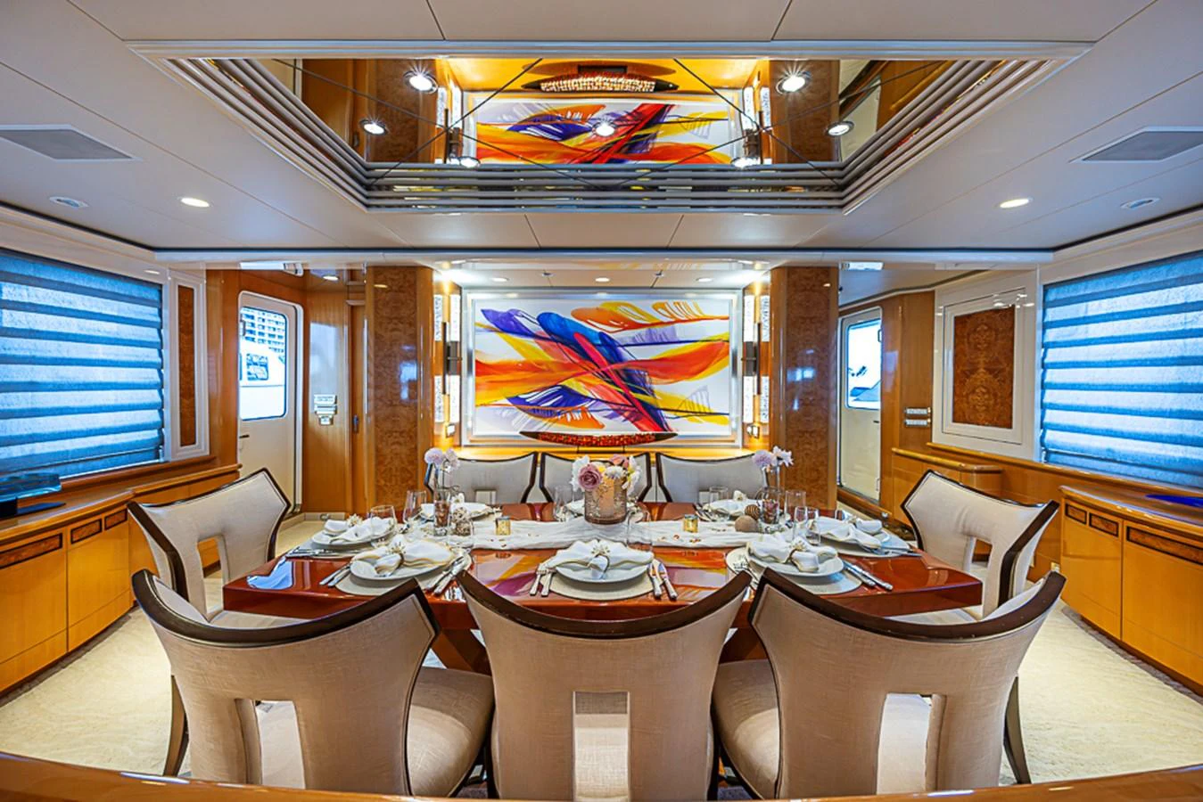 The yacht's dining area features an elegant table set for a formal meal, surrounded by plush chairs and vibrant artwork. aboard PROBABILITY Yacht for Sale