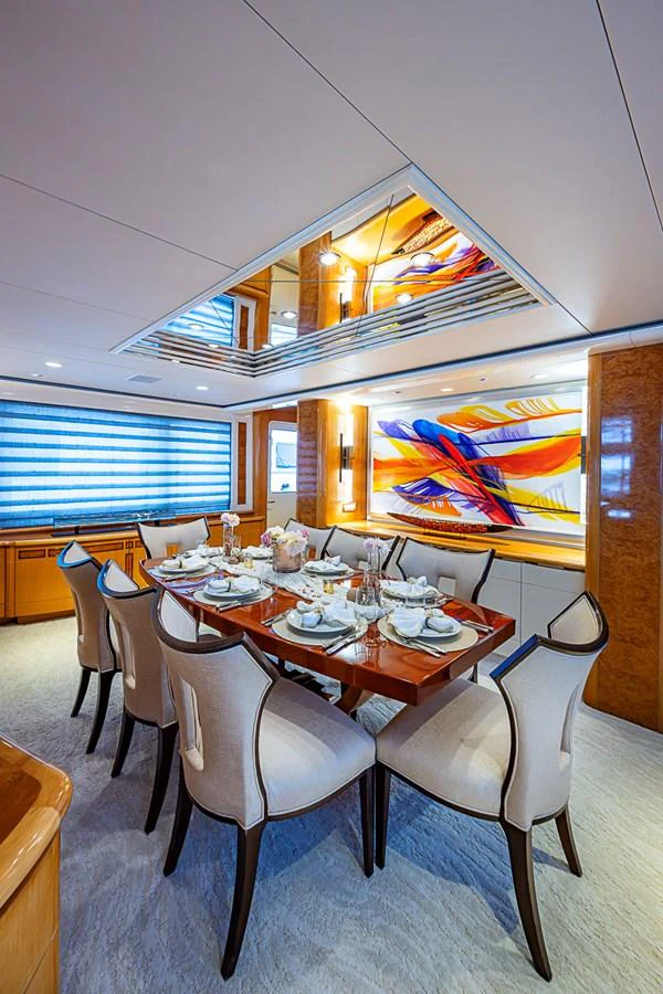 The yacht's dining area features a beautifully set table with elegant chairs and vibrant artwork on the wall. aboard PROBABILITY Yacht for Sale