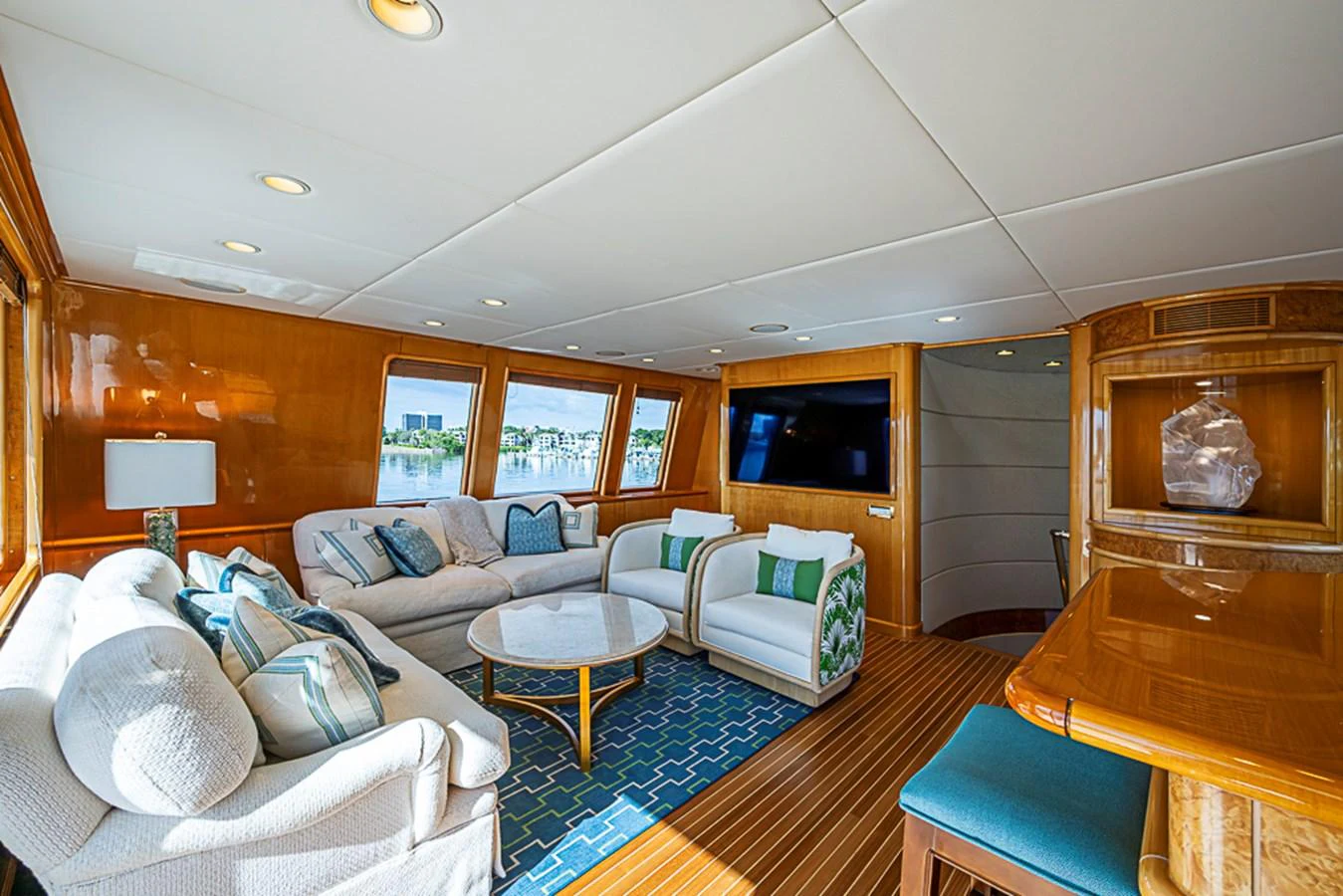 The salon features plush seating, a large flat-screen TV, and ample natural light from the surrounding windows. aboard PROBABILITY Yacht for Sale