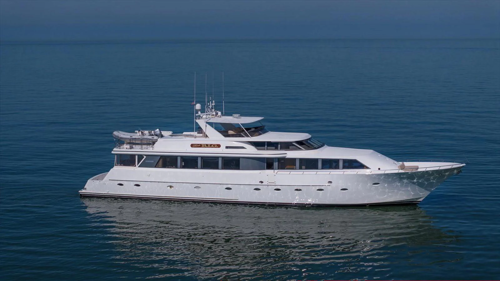 A sleek and modern yacht cruising on calm waters under a clear sky. aboard THINK B.I.G Yacht for Sale
