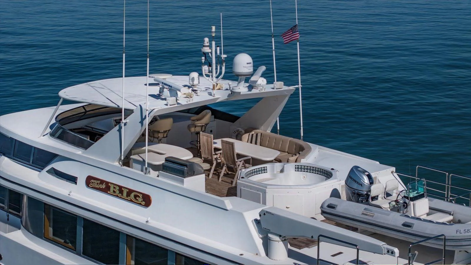 The yacht's upper deck features a spacious seating area with a hot tub and a tender at the stern. aboard THINK B.I.G Yacht for Sale