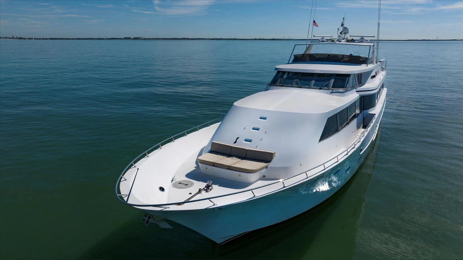 A sleek yacht glides gracefully on calm waters under a clear blue sky. aboard THINK B.I.G Yacht for Sale