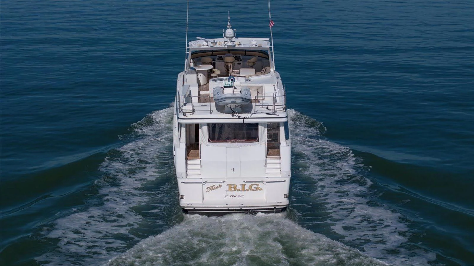 A luxurious yacht cruises smoothly on calm waters, showcasing its elegant design from the rear view. aboard THINK B.I.G Yacht for Sale