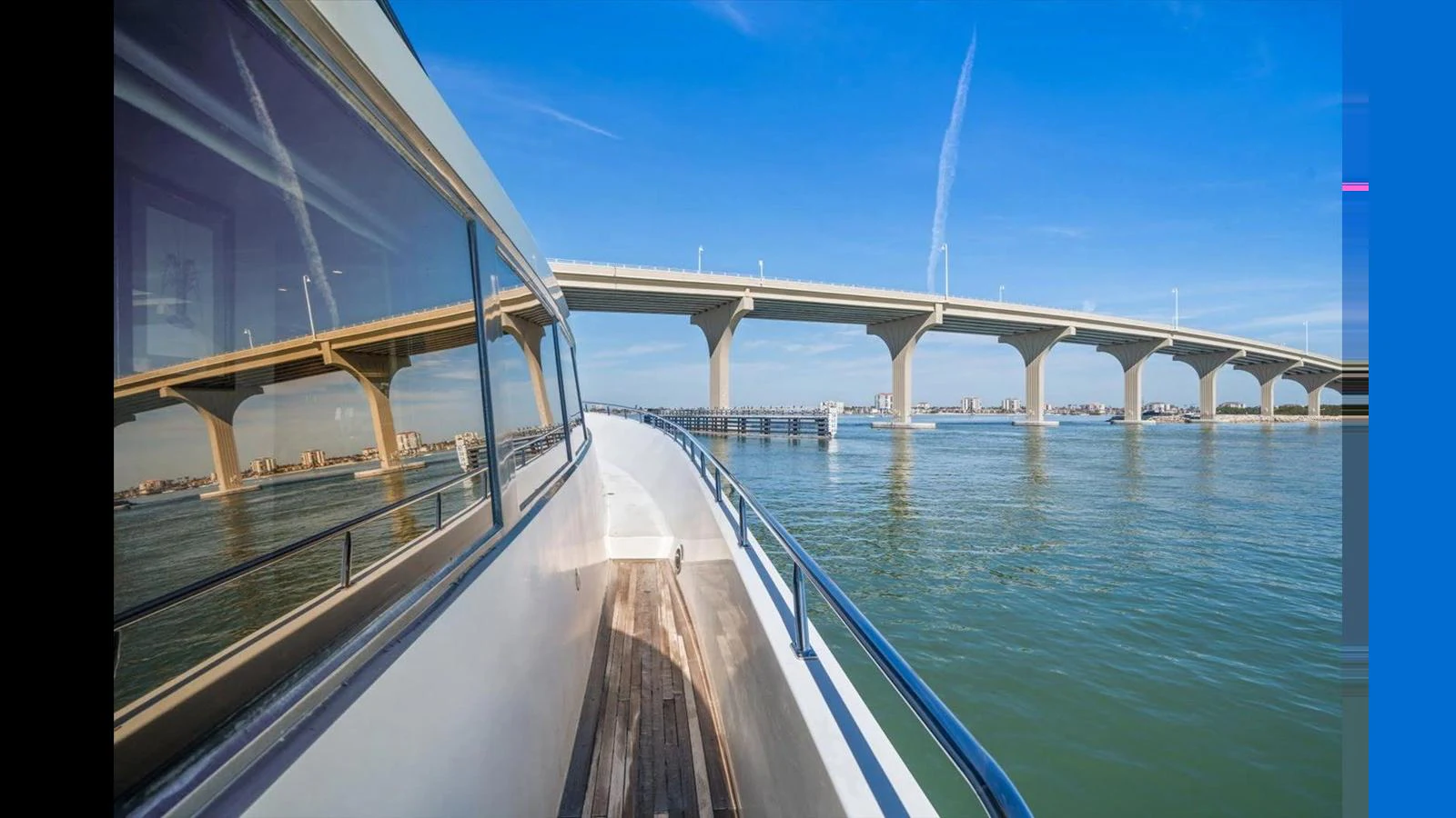 A sleek yacht cruises under a clear blue sky, reflecting the surrounding scenery on its polished surfaces. aboard THINK B.I.G Yacht for Sale
