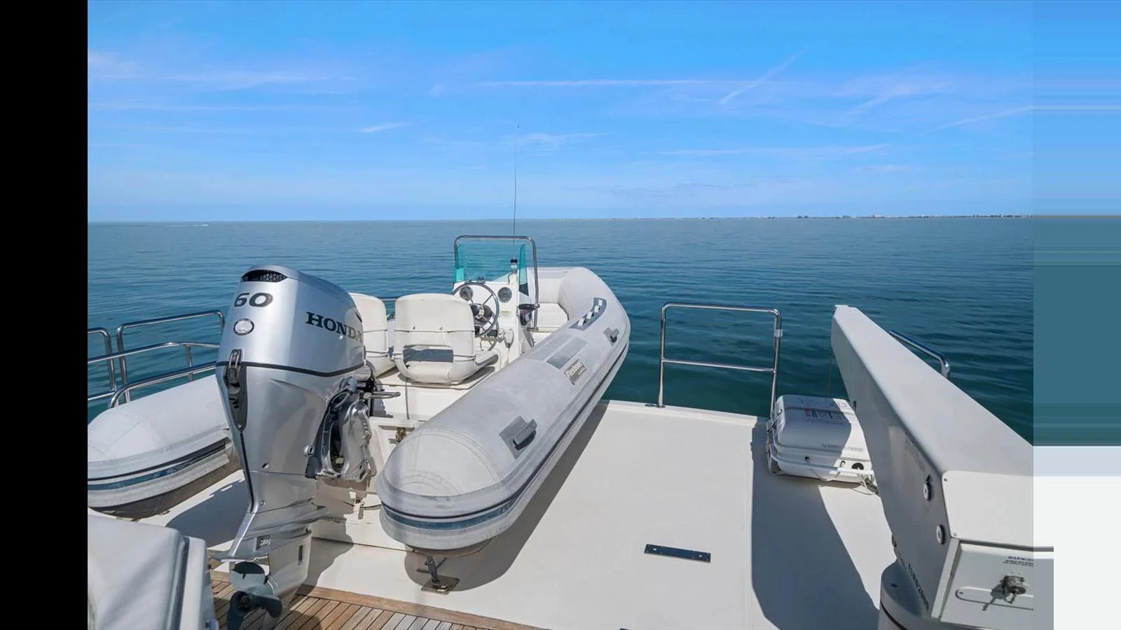 A spacious deck area featuring a tender boat with an outboard motor, perfect for exploring nearby waters. aboard THINK B.I.G Yacht for Sale