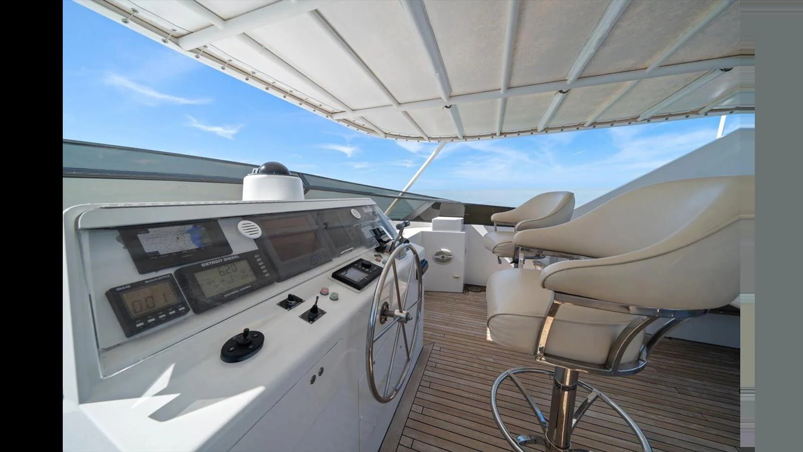 The yacht's helm station features modern navigation equipment and comfortable seating under a shaded canopy. aboard THINK B.I.G Yacht for Sale