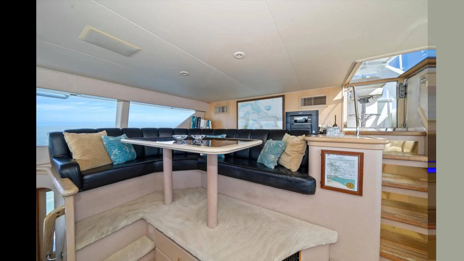 The yacht's salon features a cozy seating area with a table, plush cushions, and ample natural light. aboard THINK B.I.G Yacht for Sale