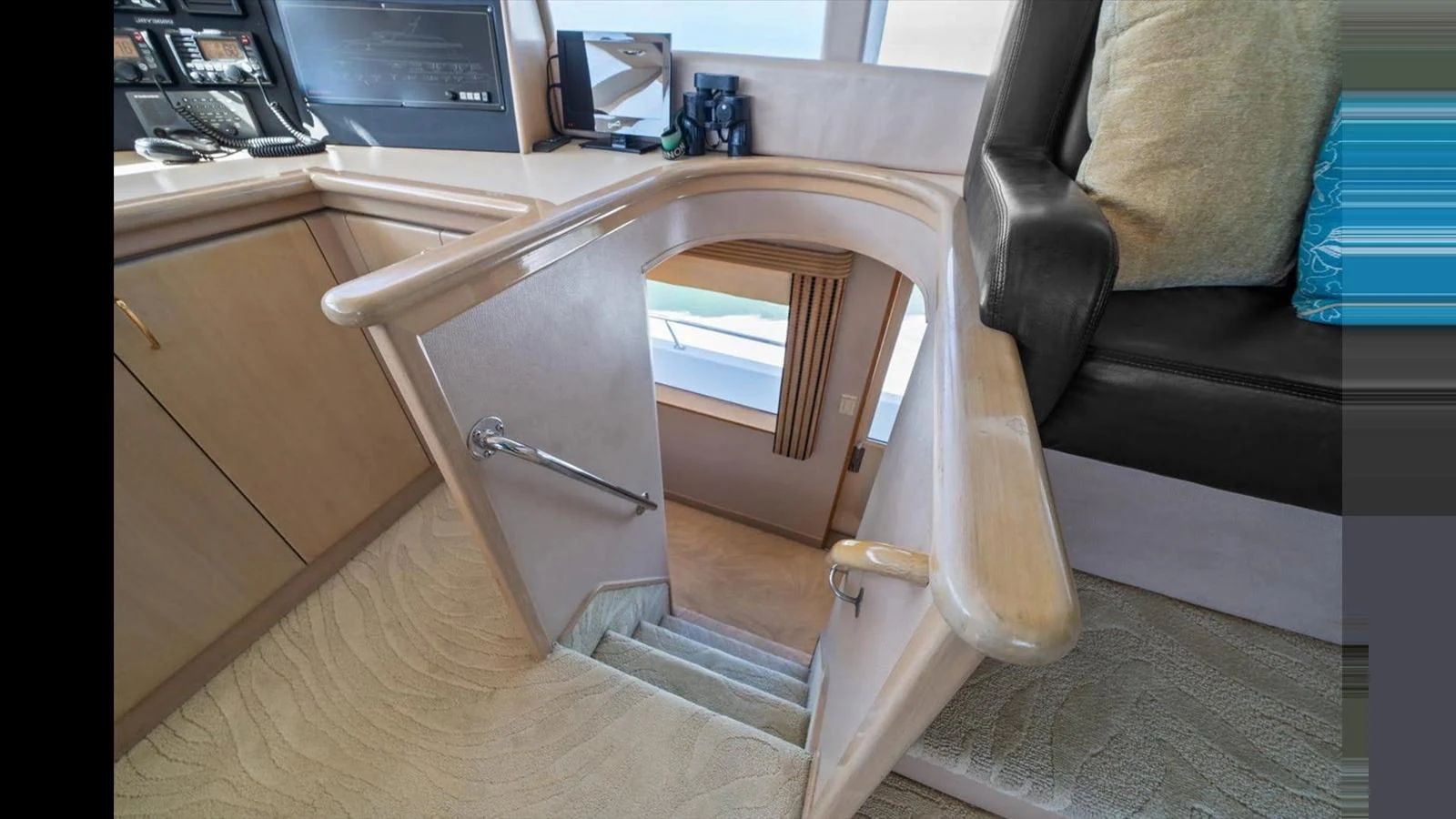 A cozy interior stairway leads to the lower deck, showcasing elegant wood finishes and plush carpeting. aboard THINK B.I.G Yacht for Sale
