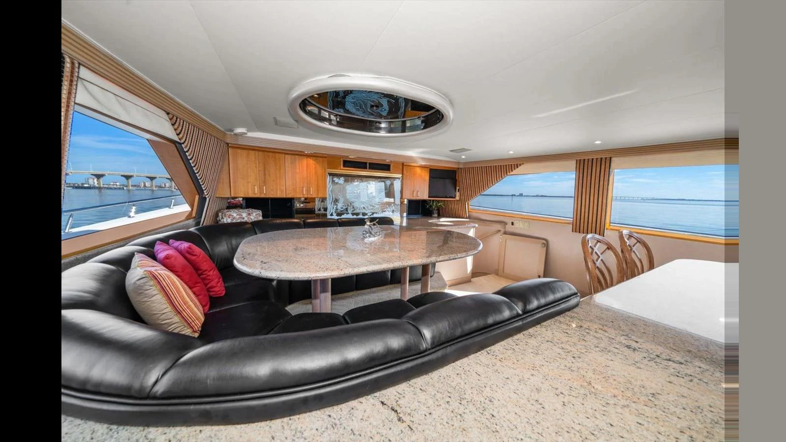 The salon features a luxurious seating area with a large granite table and panoramic windows offering stunning sea views. aboard THINK B.I.G Yacht for Sale