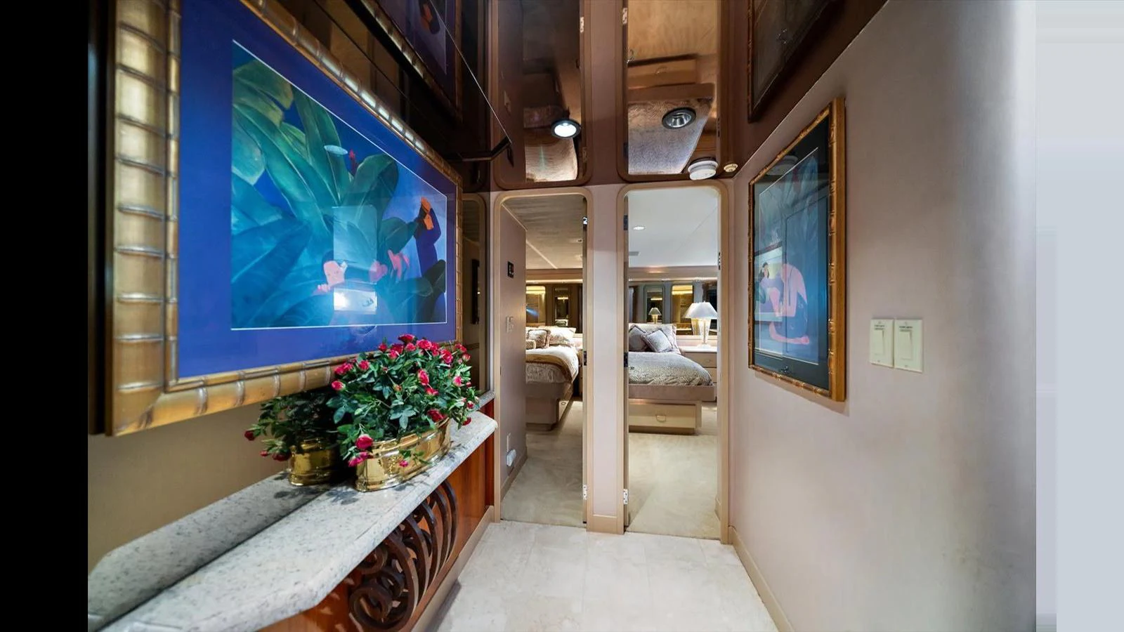 The image showcases a luxurious hallway leading to a well-appointed stateroom, adorned with vibrant artwork and elegant decor. aboard THINK B.I.G Yacht for Sale