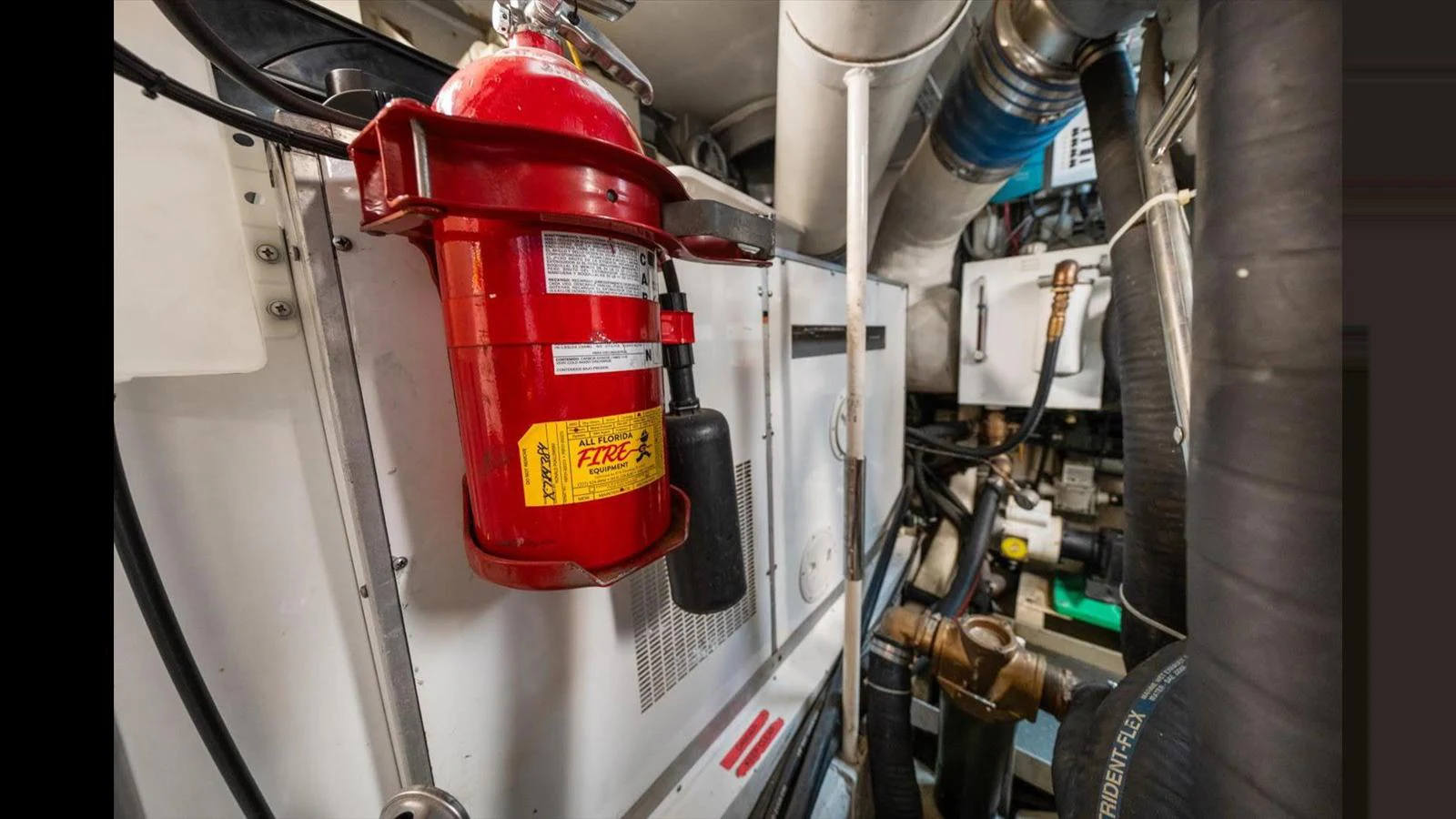 The image showcases the engine room with a focus on a fire extinguisher and various mechanical components. aboard THINK B.I.G Yacht for Sale