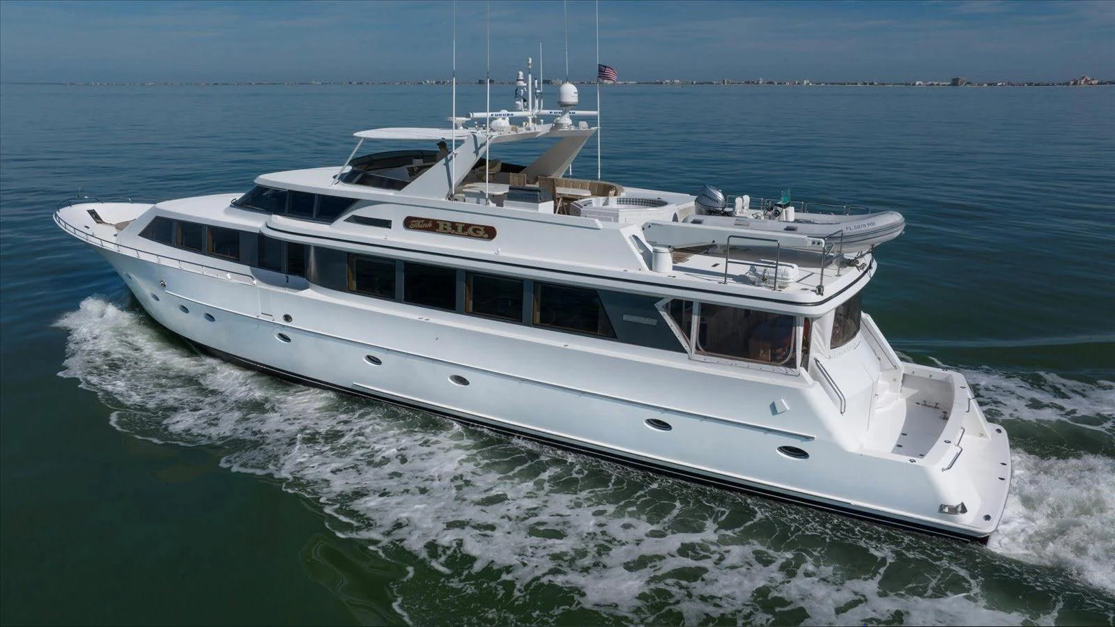 A sleek white yacht cruises smoothly on calm waters under a clear sky. aboard THINK B.I.G Yacht for Sale