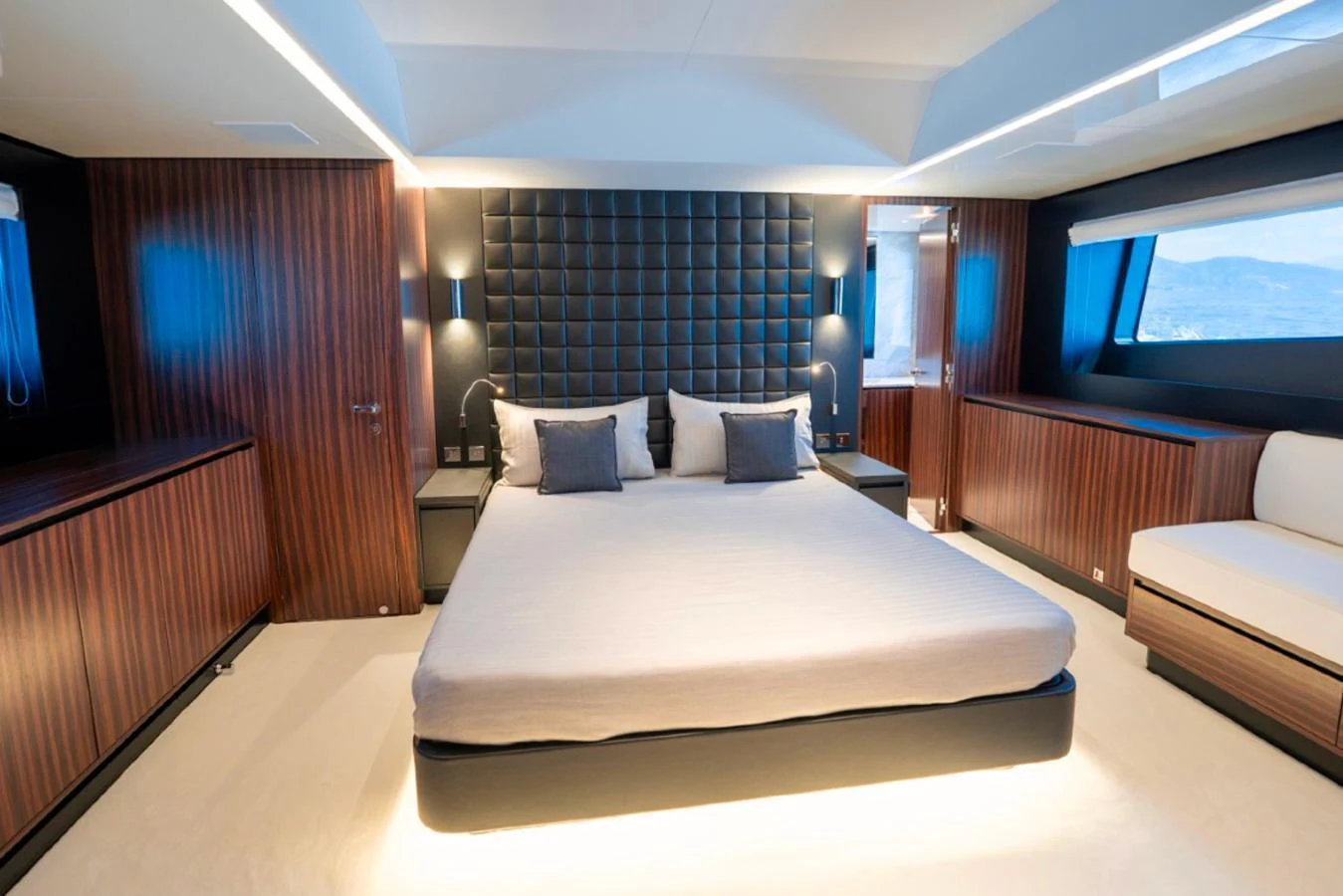 The master stateroom features a luxurious bed with modern lighting and elegant wood paneling. aboard COCO Y Yacht for Sale