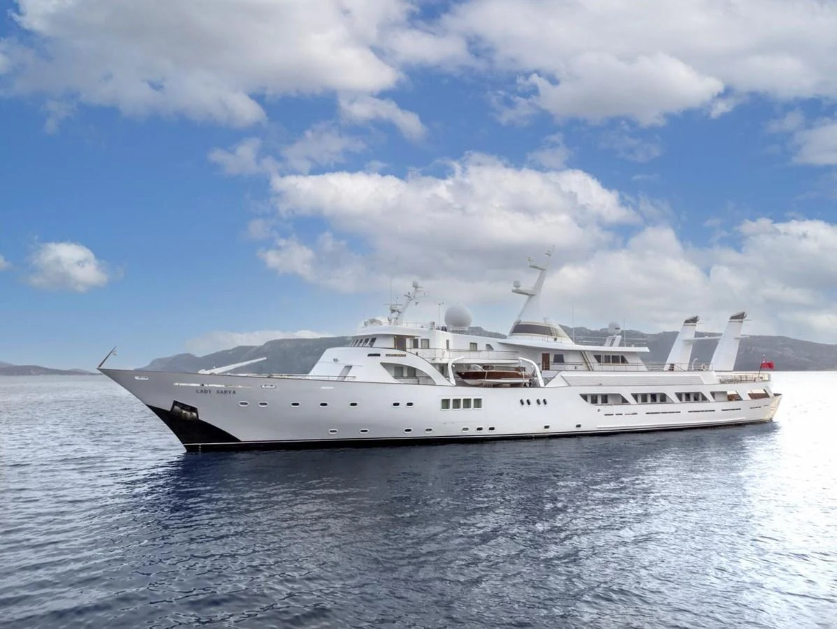 A majestic yacht glides gracefully on calm waters under a partly cloudy sky. aboard LADY SARYA Yacht for Sale