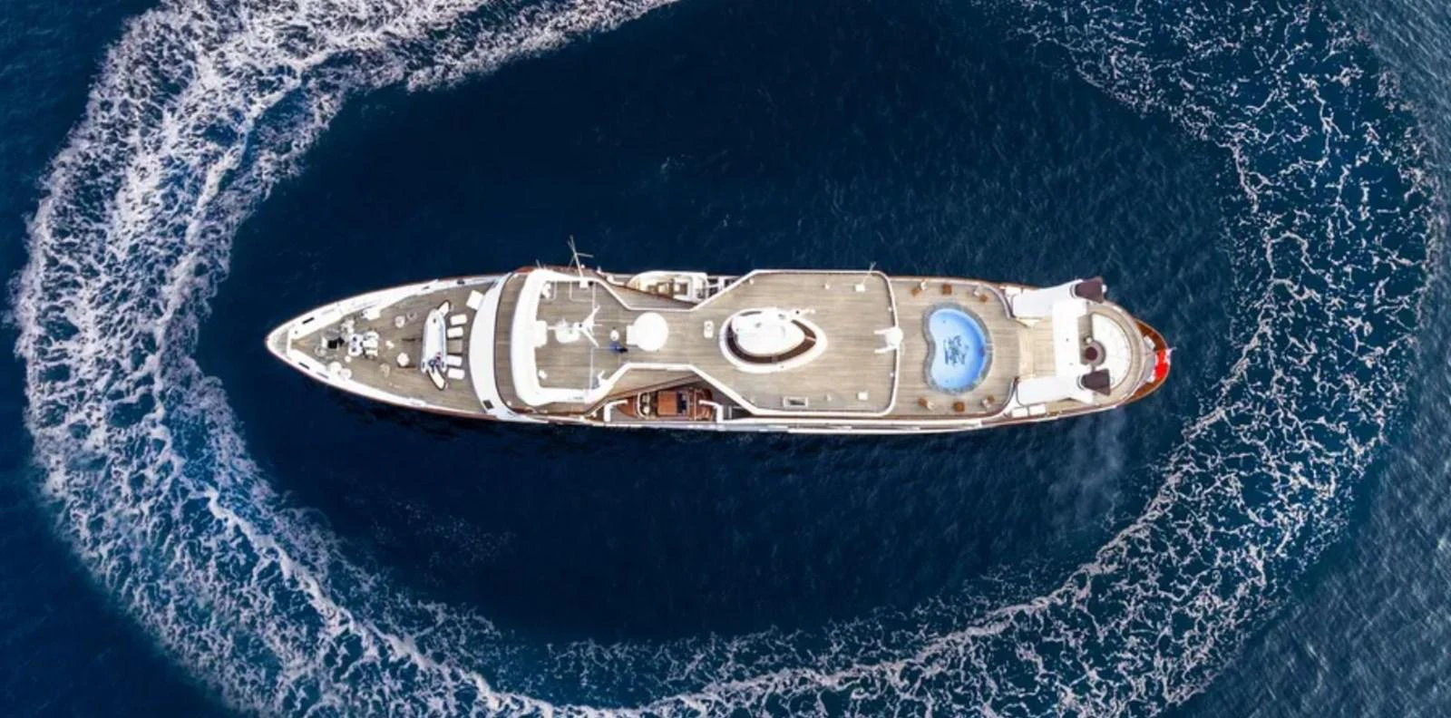 A stunning aerial view of a luxurious yacht cruising through the open sea, showcasing its expansive deck and onboard pool. aboard LADY SARYA Yacht for Sale