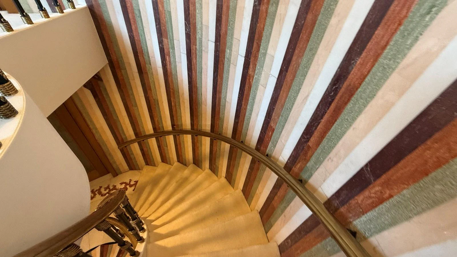 A luxurious spiral staircase with colorful striped walls creates a striking visual effect. aboard LADY SARYA Yacht for Sale