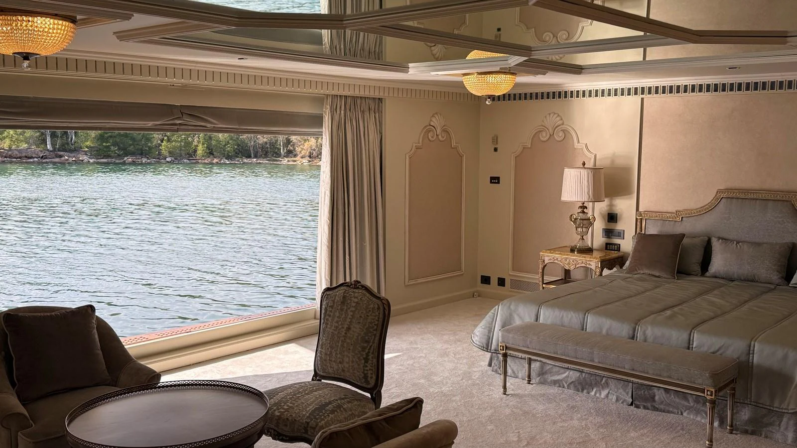 The luxurious stateroom offers a serene view of the water through a large window, complemented by elegant furnishings and soft lighting. aboard LADY SARYA Yacht for Sale