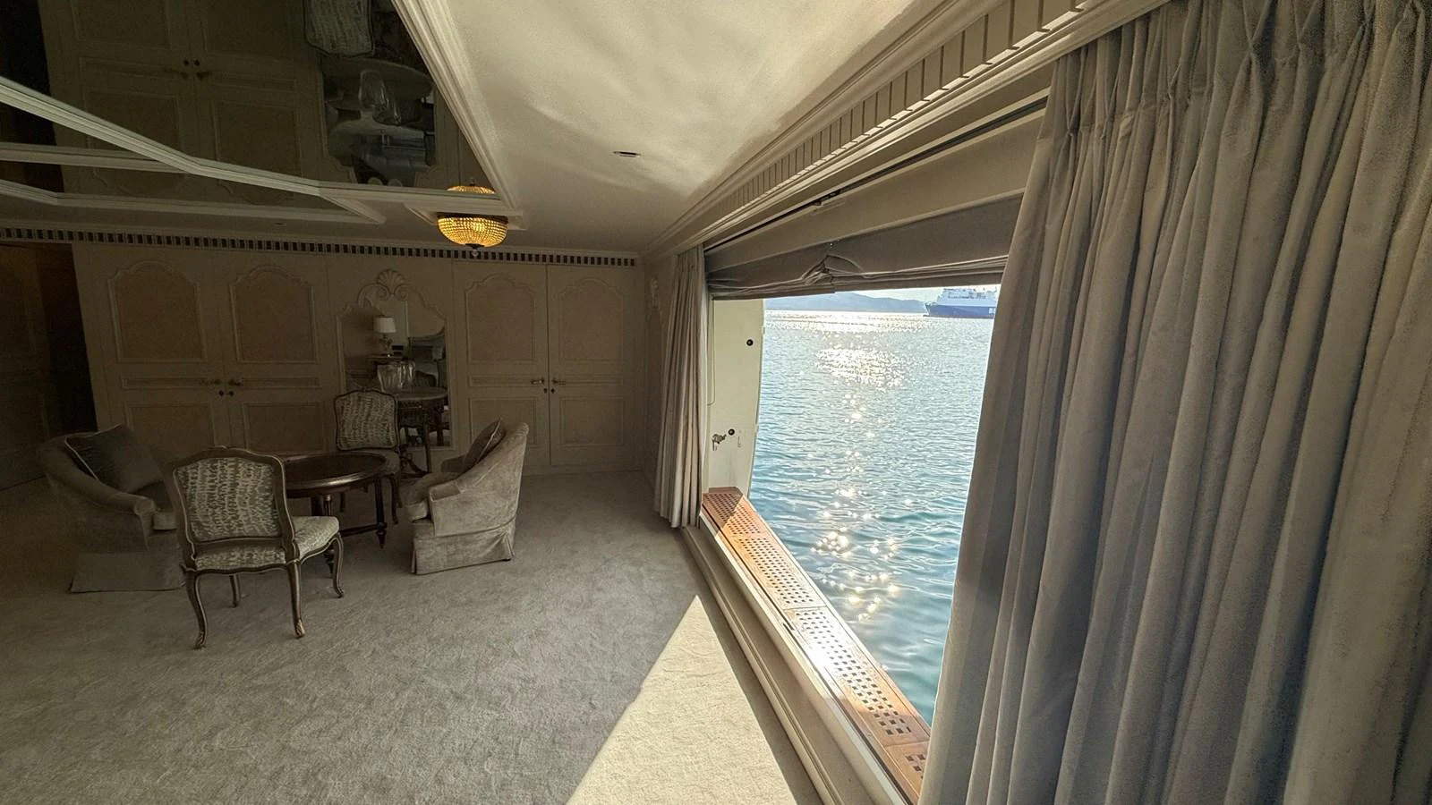 A luxurious interior space with elegant furnishings and a large window offering a stunning view of the water. aboard LADY SARYA Yacht for Sale