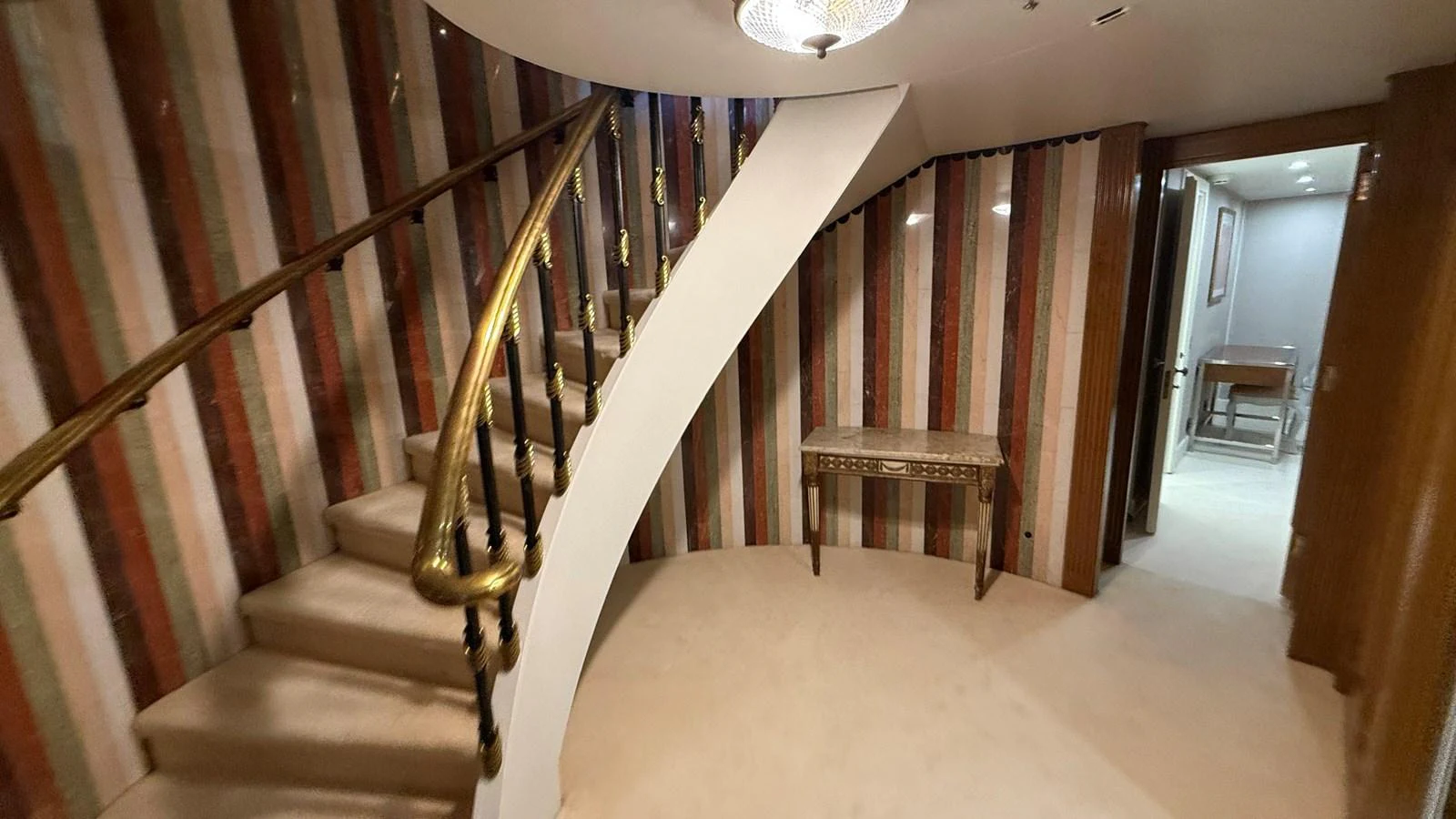 A luxurious interior staircase with elegant brass handrails and striped wall decor. aboard LADY SARYA Yacht for Sale