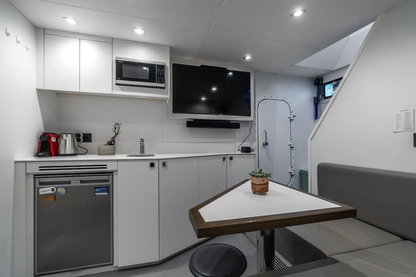 a kitchen with a table and a tv aboard AURELIUS Yacht for Sale