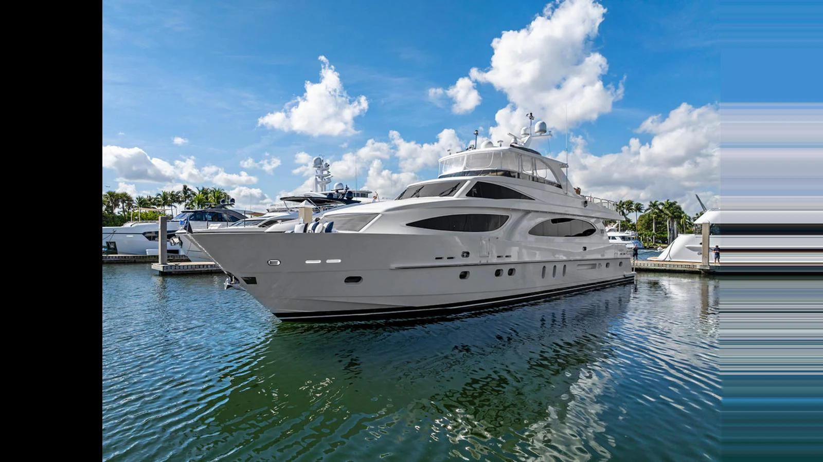 A sleek and modern yacht is docked in a serene marina under a bright blue sky. aboard PERFECT HARMONY Yacht for Sale