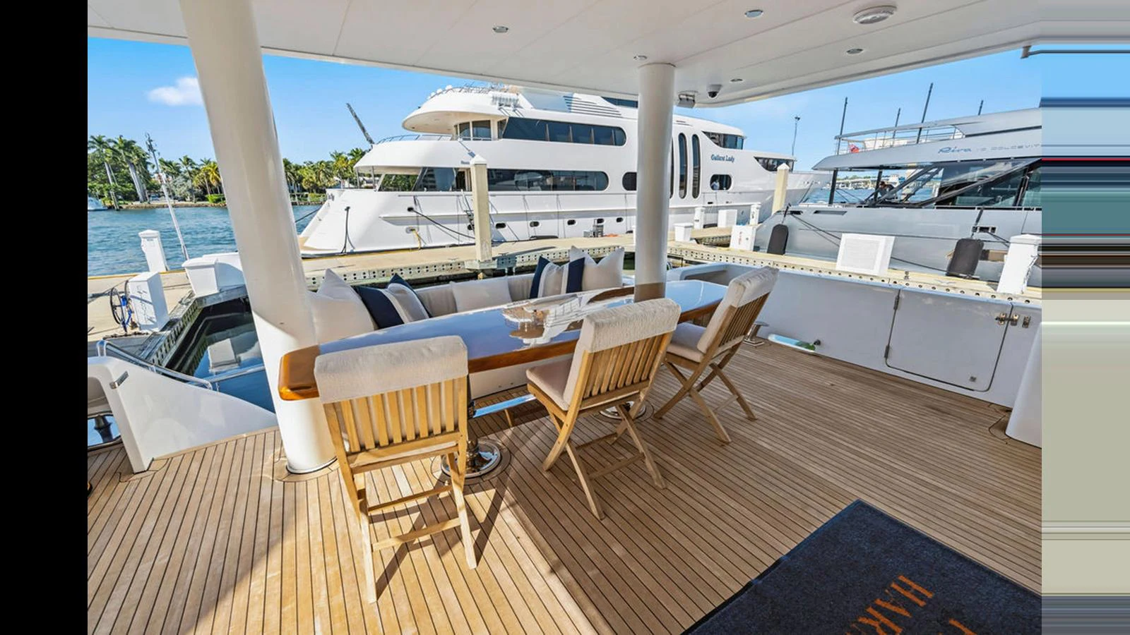 The aft deck features a stylish dining area with a wooden table and comfortable chairs, perfect for alfresco meals. aboard PERFECT HARMONY Yacht for Sale