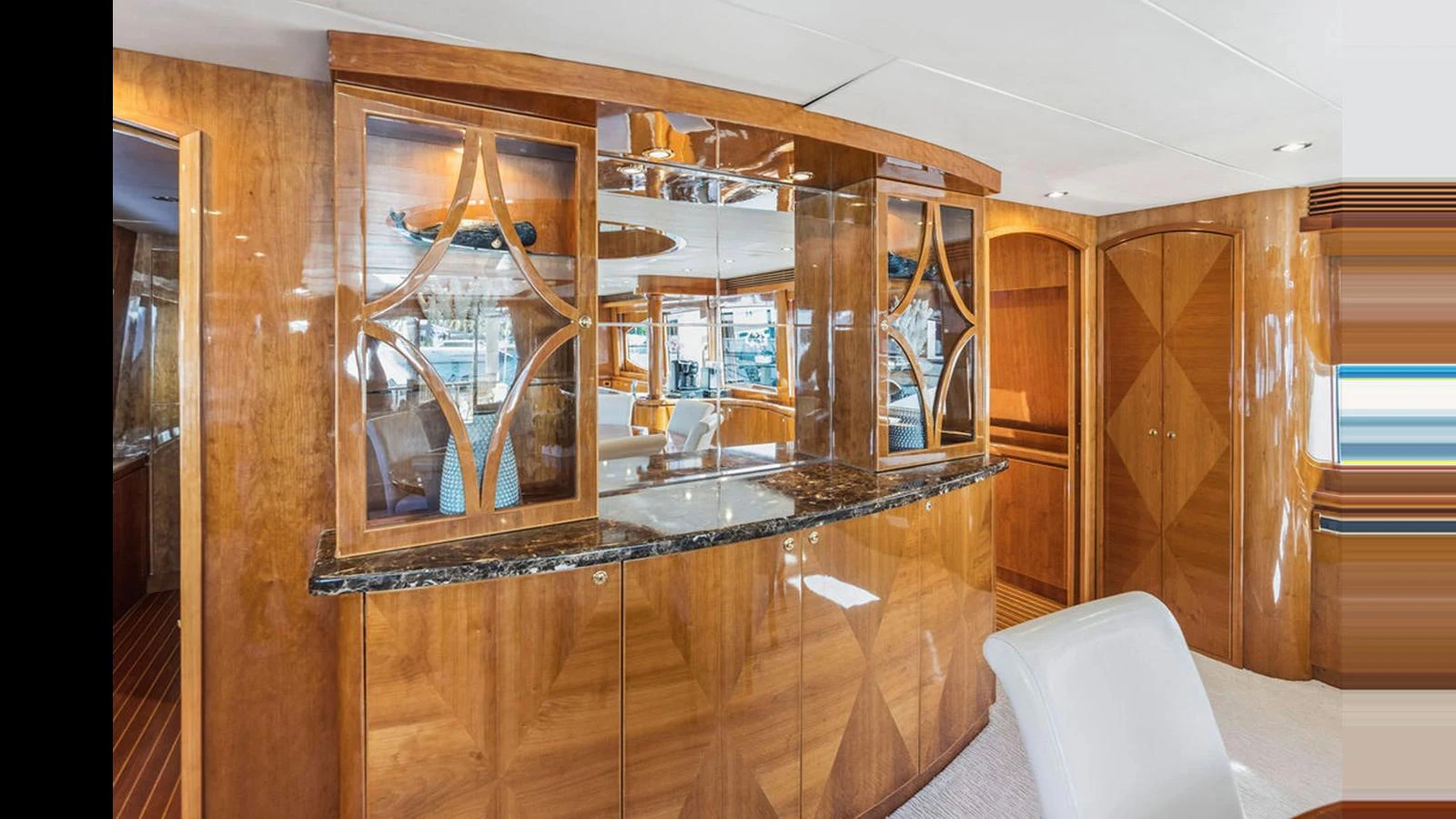 The yacht's salon features elegant wood cabinetry and a sleek bar area with a luxurious marble countertop. aboard PERFECT HARMONY Yacht for Sale