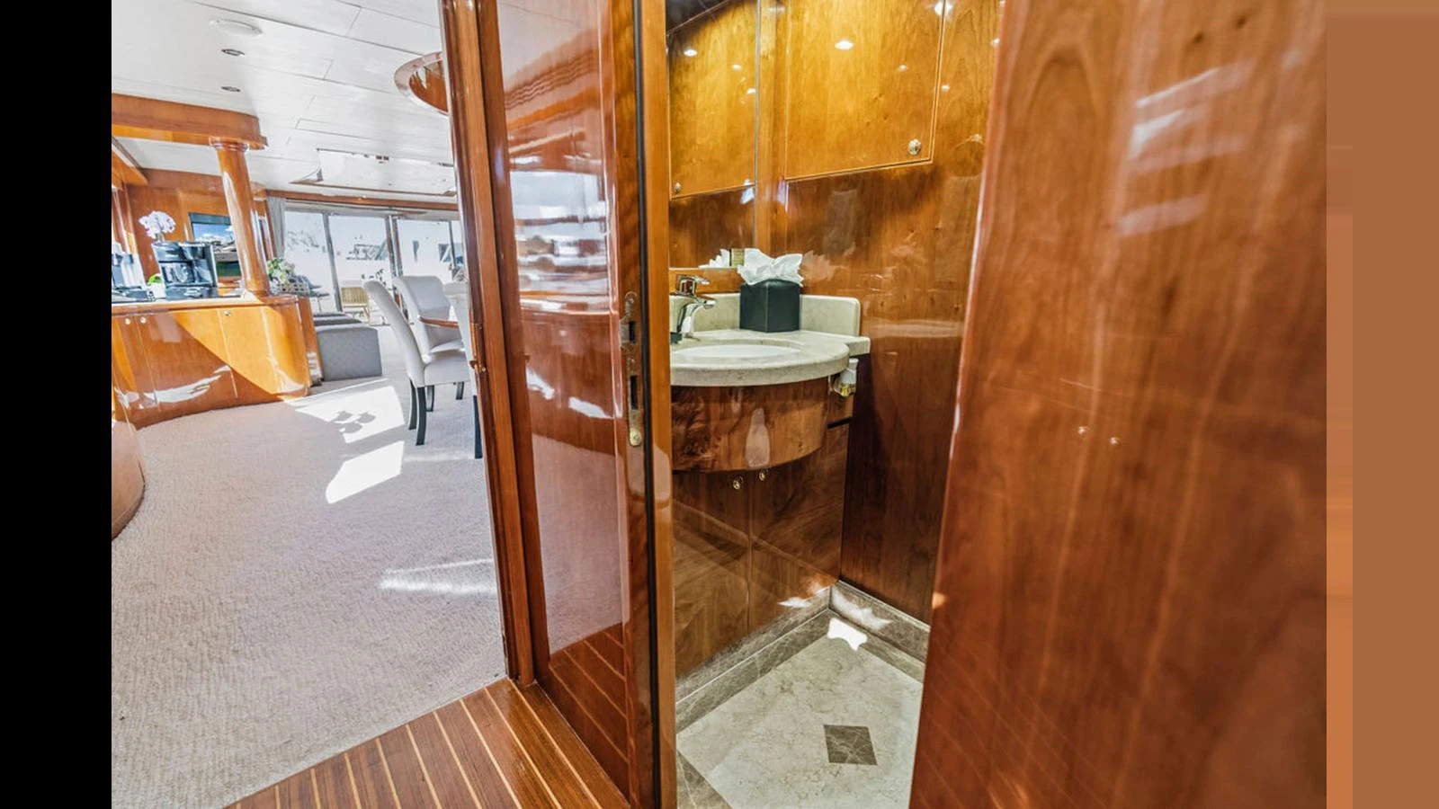 The image showcases a luxurious yacht interior featuring a well-appointed head with rich wood finishes and a marble sink. aboard PERFECT HARMONY Yacht for Sale