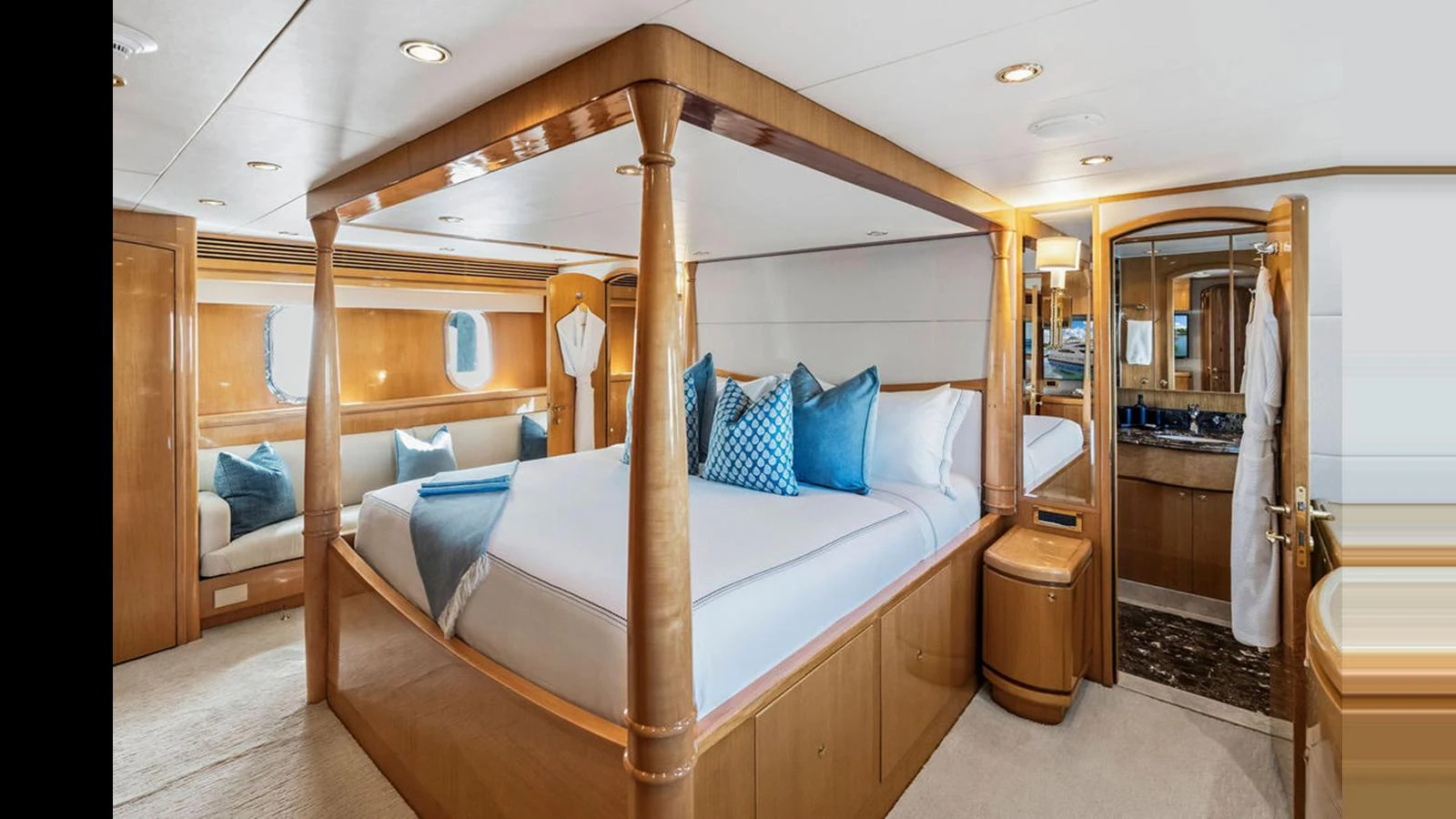 The master stateroom features a luxurious four-poster bed with elegant wood finishes and plush blue accents. aboard PERFECT HARMONY Yacht for Sale