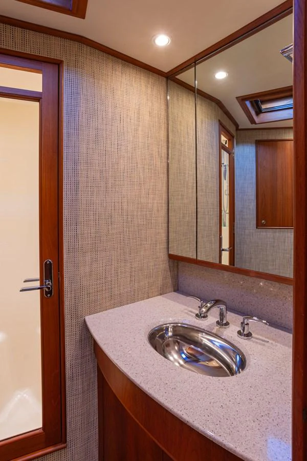 The yacht's bathroom features elegant wood finishes and a sleek countertop with a modern sink. aboard HT HOOK Yacht for Sale