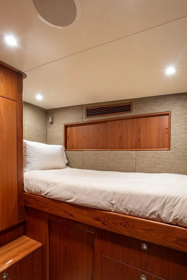 A cozy yacht cabin featuring a comfortable bed with wooden accents and soft lighting. aboard HT HOOK Yacht for Sale