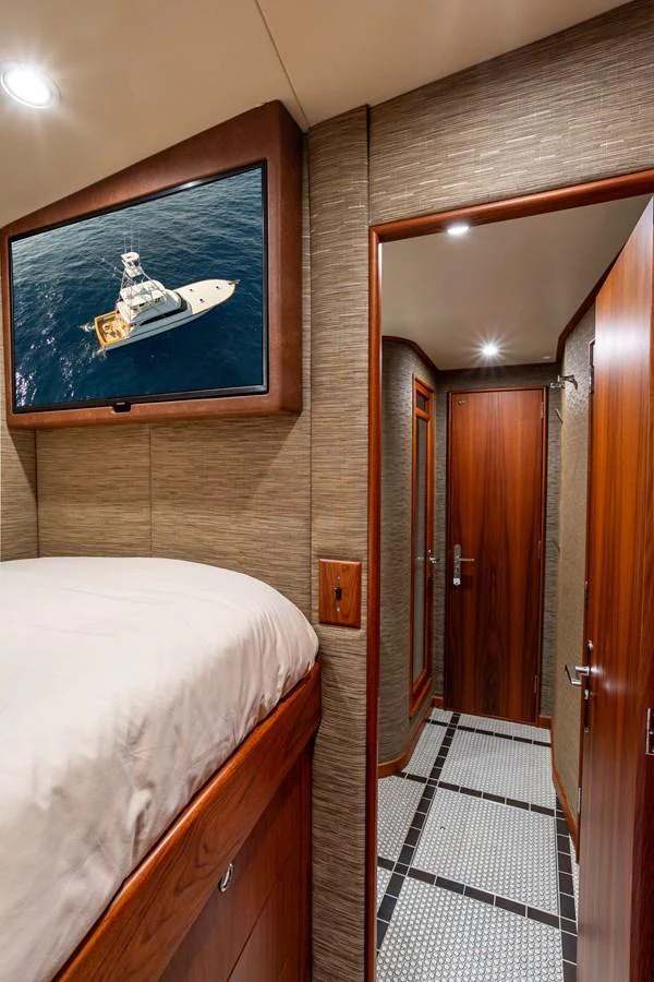 A cozy stateroom with a wall-mounted TV and elegant wood finishes. aboard HT HOOK Yacht for Sale