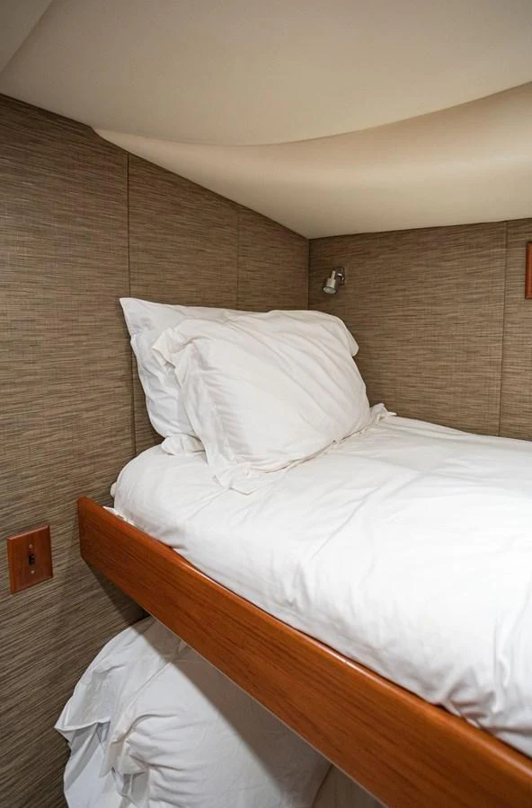 The cozy bunk bed cabin features plush white bedding and warm wood accents. aboard HT HOOK Yacht for Sale