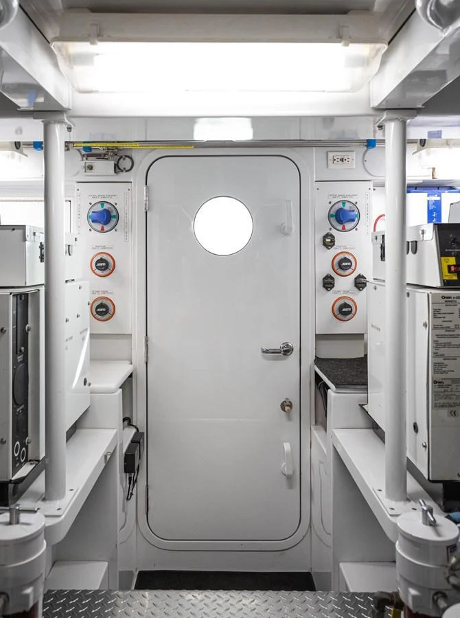 A well-organized and functional yacht engine room with a central door and various control panels. aboard HT HOOK Yacht for Sale