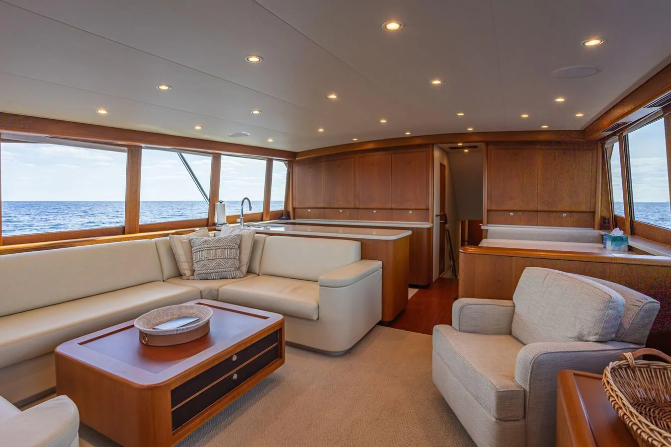 The salon features plush seating, warm wood finishes, and expansive windows offering stunning ocean views. aboard HT HOOK Yacht for Sale